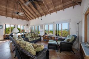 sala de estar con sofás, sillas y ventanas en Chez Cay Cottage cottage, en Governorʼs Harbour