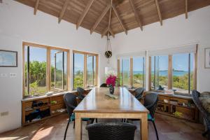 ein Esszimmer mit einem Tisch, Stühlen und Fenstern in der Unterkunft Chez Cay Cottage cottage in Governors Harbour