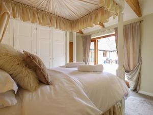a bedroom with a large white bed with a canopy at The Stables at Hall Barn in Diss