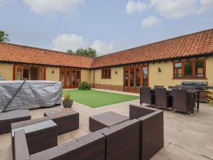 an outdoor patio with chairs and a lawn at The Stables at Hall Barn in Diss