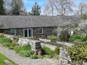 una casa de piedra con un jardín delante de ella en The Garden Room, en Hexham