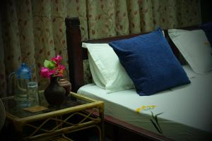 a bed with a blue pillow and a table with flowers at Sambodhi Yoga Home in Kathmandu