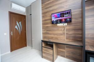 Cette chambre dispose d'une télévision sur un mur en bois. dans l'établissement Avangard, à Batoumi