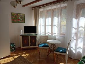 a living room with a television and a table and chairs at Apartament u Izy in Kazimierz Dolny