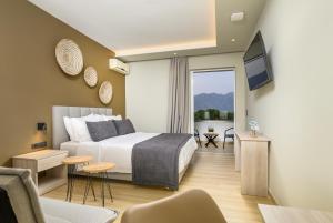 カルダメナにあるNicolas Grand Suites, Adults Onlyのベッドとテレビが備わるホテルルームです。