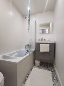 ein weißes Badezimmer mit einer Badewanne und einem Waschbecken in der Unterkunft Appartement cosy Le Saint Gildas, à proximité immédiate centre ville, place de stationnement, Netflix in Vannes