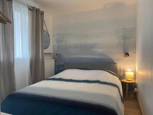 Schlafzimmer mit einem blauen und weißen Bett und einem Fenster in der Unterkunft Appartement cosy Le Saint Gildas, à proximité immédiate centre ville, place de stationnement, Netflix in Vannes