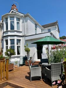 um deque de madeira com uma mesa, cadeiras e um guarda-sol em Bentley Lodge em Torquay