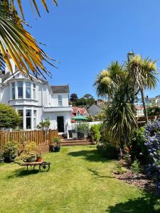 una casa blanca con un patio con palmeras en Bentley Lodge en Torquay