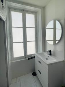 ein weißes Badezimmer mit einem Waschbecken und einem Spiegel in der Unterkunft Corner cocoon in the center of La Rochelle in La Rochelle