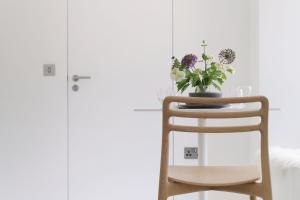 a chair with a vase of flowers on it at Eastside - Architect designed retreat with wood-fired sauna in Penicuik