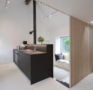 a kitchen with a sink and a living room at Eastside - Architect designed retreat with wood-fired sauna in Penicuik