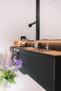 a kitchen with a sink and a table with flowers at Eastside - Architect designed retreat with wood-fired sauna in Penicuik