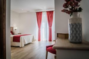 Segura de LeónにあるHOTEL RURAL LA TEJAのベッドと赤いカーテンが備わるホテルルームです。