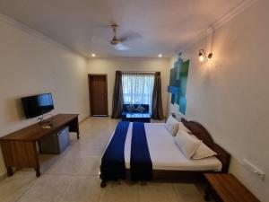 a bedroom with a bed and a desk and a television at Rishikesh Resort Lonavala in Lonavala
