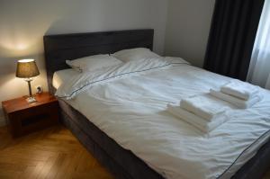 Una cama con sábanas blancas y toallas. en Almi Apartment, Villa Moderno z podziemnym parkingiem en Toruń