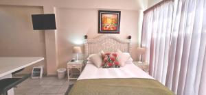 a bedroom with a bed with white sheets and pillows at Sea la vie Self Catering Studio Apartment in Gordonʼs Bay