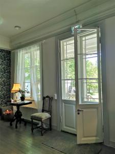 a room with a chair and a table and windows at Villa Björksten in Loviisa