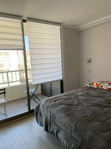 a bedroom with a bed and a window with blinds at Cómodo y Nuevo Depto. Amoblado in Iquique