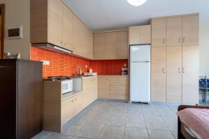 een keuken met houten kasten en een witte koelkast bij Cleri's Studio in Néa Péramos