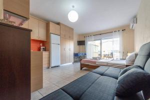 een woonkamer met een blauwe bank en een keuken bij Cleri's Studio in Néa Péramos