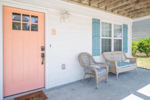 a porch with two chairs and a red door at Completely Remodeled - Beach Access 3 Doors Down - Near Kure Beach Pier in Kure Beach