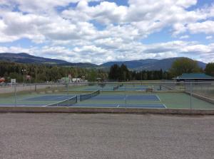 ein paar Tennisplätze mit Bergen im Hintergrund in der Unterkunft Ace Western Motel in Clearwater