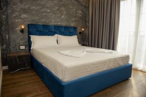 a large bed with a blue headboard in a bedroom at Hotel Royal in Shkodër