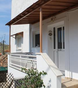 a white house with a porch and a deck at Dabia Apartments in Mirina