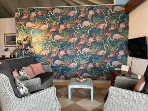 una sala de estar con un gran mural de flamencos rosas en Tip! Blue Bay Beachvilla 12 - Blue Bay Resort en Dorp Sint Michiel