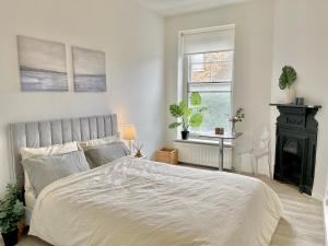a white bedroom with a bed and a fireplace at Archway Station Big Bedroom Flat in London