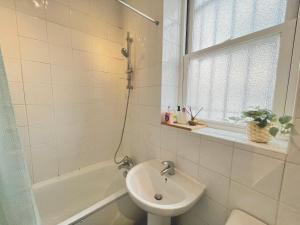a bathroom with a sink and a bath tub with a window at Archway Station Big Bedroom Flat in London