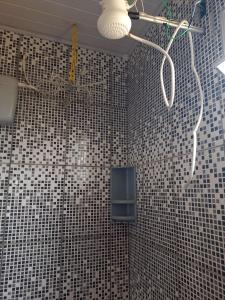 a bathroom with a ceiling fan and a tiled wall at Chalé Nascer do Sol in São Thomé das Letras +81 photos