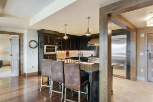 a kitchen with black cabinets and a bar with bar stools at Edgemont 2605 - Luxury Ski-in Ski-out Condo in Steamboat Springs +5 photos