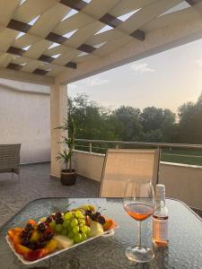 烏爾齊尼的住宿－Robi Apartments，桌上的水果和一杯葡萄酒