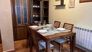 una mesa de madera con sillas, platos y copas de vino en Casa gorgona, en León