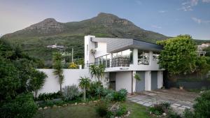 a white house with a mountain in the background at Noordhoek Bliss Beach House in Cape Town