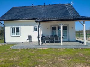 una casa blanca con una terraza con sillas. en Domek Relaks pod Śnieżką, en Miłków