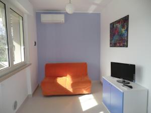 una sedia arancione seduta in una stanza con televisore di Villa Il Melograno a Vasto
