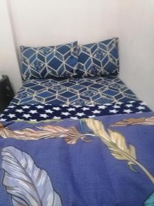 een bed met blauwe en witte lakens en kussens bij Matinxs Home in Abu Dhabi