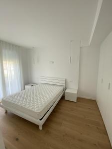Camera bianca con letto e pavimento in legno. di Sirio 7 a Lido di Jesolo