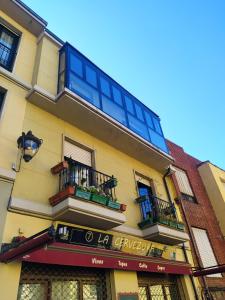 żółty budynek z balkonami i znakiem na nim w obiekcie Apartamento plaza Mayor / Húmedo w mieście León