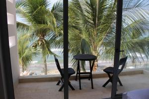 a room with two chairs and a table and a palm tree at Hotel Casa Danae in Tolú