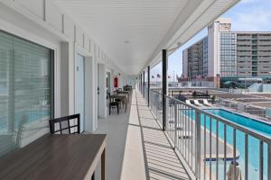 a balcony with tables and chairs and a pool at The Beach House in Wildwood