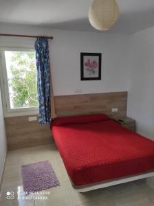 1 dormitorio con cama roja y ventana en Alojamiento Playa Centro Corralejo 16 en Corralejo