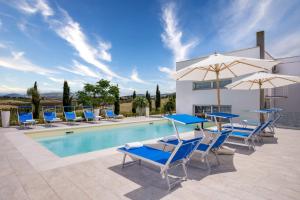 a pool with blue chairs and umbrellas next to a building at Villa Sikelia in Alcamo