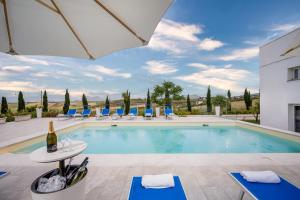 - une piscine avec des chaises et une bouteille de vin dans l'établissement Villa Sikelia, à Alcamo