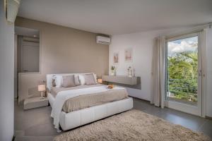 a white bedroom with a large bed and a window at Villa Sikelia in Alcamo