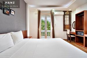- une chambre avec un grand lit blanc et un bureau dans l'établissement HANZ AMI Central Hotel Hanoi, à Hanoï