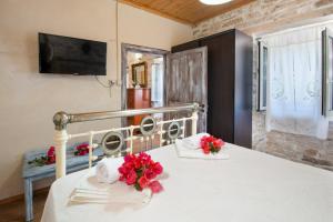 a bedroom with a white bed with red flowers on it at Ionian Stone Home with Terrace in Bogdanátika